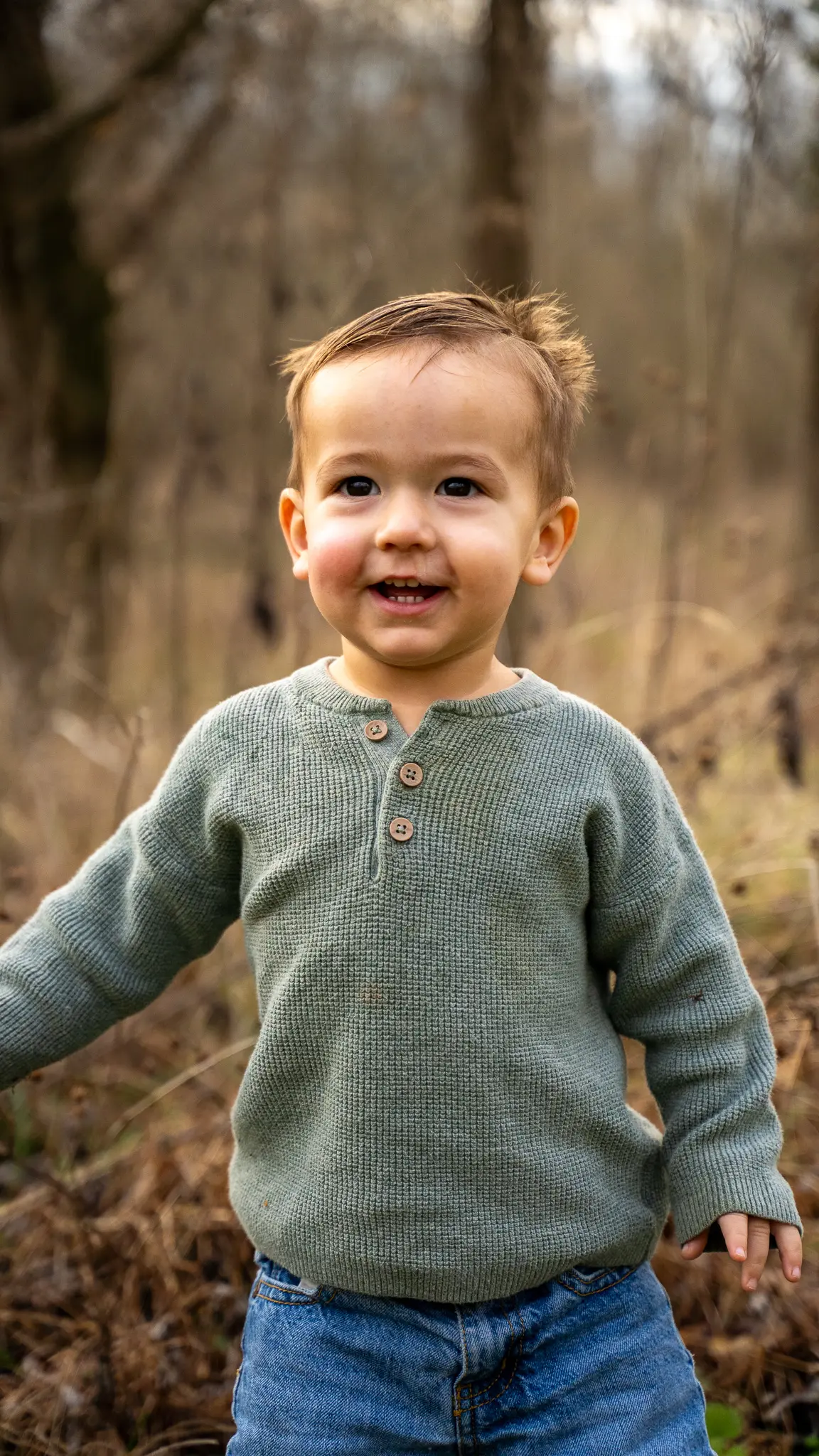 Toddler boy in a green sweater in an autumn field